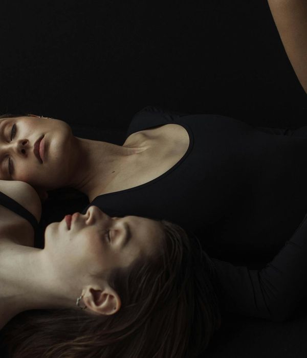Woman in a calm, graceful yoga pose in a dark studio.